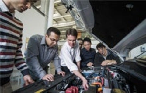 McPhee and students looking at parts of a car