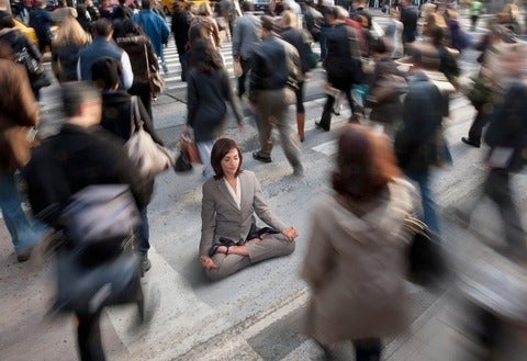 Woman dressed in business suite practicing yoga in busy urban crosswalk