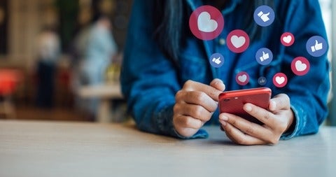 person's sitting behind a tables scrolling on their smart phone
