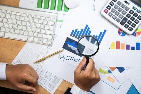 Holding magnifying glass for looking and analysis financial data