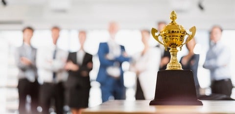 Group of professionals in the background with a trophy in the foreground 