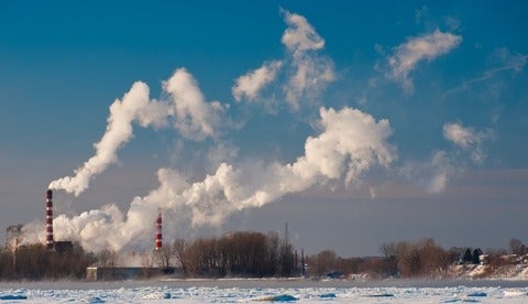 aper mill with its smokestacks spewing smoke against blue sky as across St-Lawrence River, Trois-Rivieres, Quebec, Canada.