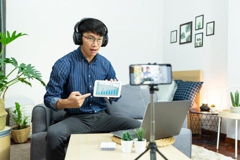 Asian man in headphones writing notes in notebook