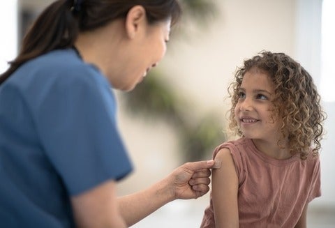 A child gets a bandaid put over their injection site in the doctor's office.