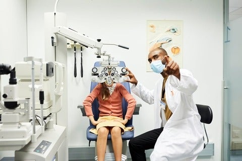Ophthalmologist gesturing to girl in hospital