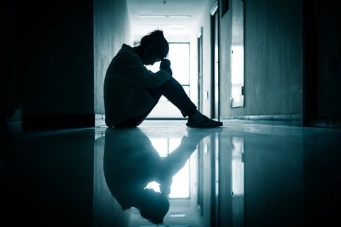 A shadowed teenage girl sitting in a hallway 