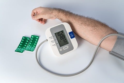 Man's arm with device for taking blood pressure and pills