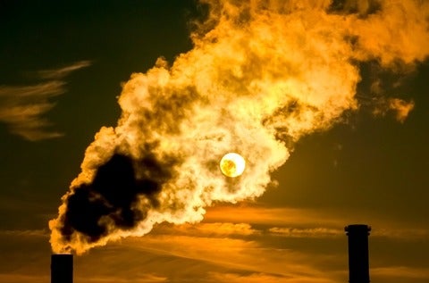 An image of smokestacks emitting smoke during a sunset