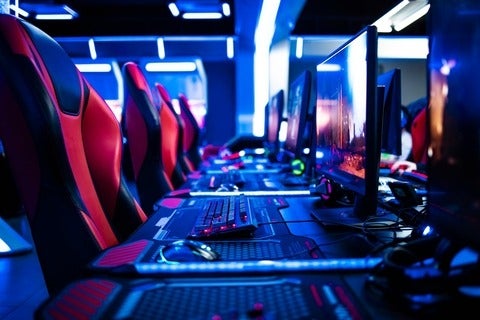 Game room interior with modern ambient lights and powerful super computers, consoles, keyboards for playing video games