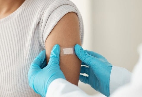 A doctor applying a band-aid after vaccinating a patient. (PeopleImages/GettyImages)
