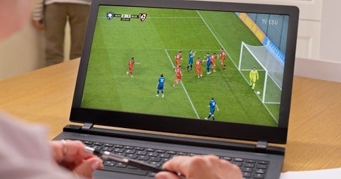 Watching a soccer match on a laptop 