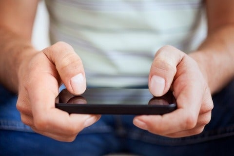 Hands of a casual man using a smartphone.