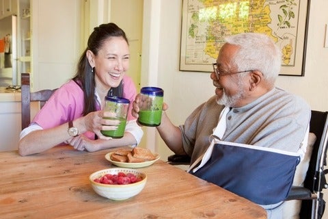 Caretaker and older man having smoothies 