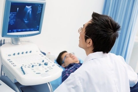 Medical practitioner using ultrasound medical device to examine patient.
