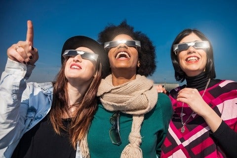 Group of friends looking to a solar eclipse wearing solar eclipse glasses.