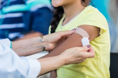 Doctor applies bandage to female's arm following an immunization
