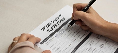 Image of someone signing a work injury claim form