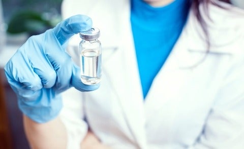 Pharmacist holds medical glass vial for vaccination. 