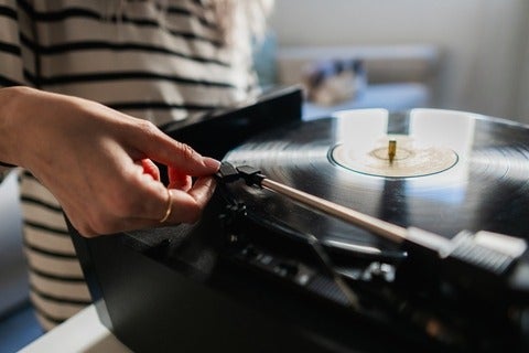 Woman places record-player needle on a record