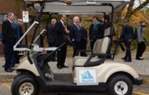 Dignitaries standing around a self-driving golf cart
