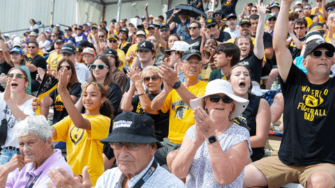 Attendees at the Homecoming football game cheering in the grandstands