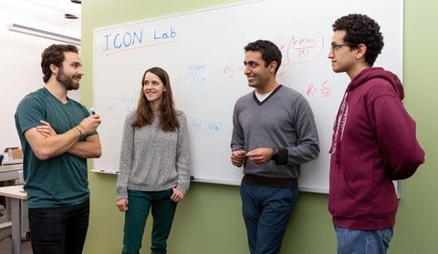 Professor Omid Abari and his students stand beside a white board