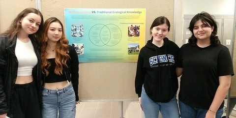 Four students sharing their poster on western science vs. Traditional Ecological Knowledge