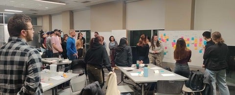Students standing looking at presentation on whiteboard in front of them