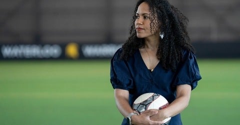 Dr. Kaleigh Pennock stands inside the field house holding a soccer ball