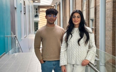 Murto Hilali and Kritika Grover standing at the top of the stairs inside the Science Teaching Complex building