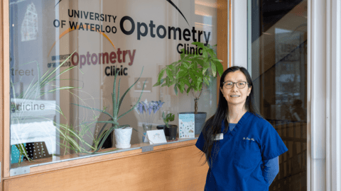 Dr. Lisa Woo standing in front of a window decal thay says "University of Waterloo Optometry Clinic."