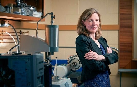 Mary Wells standing with arms crossed, next to lab equipment