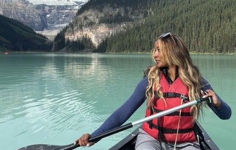 Marianna Sukhu paddles a canoe on a beautiful, clear lake while on a recreational trip.