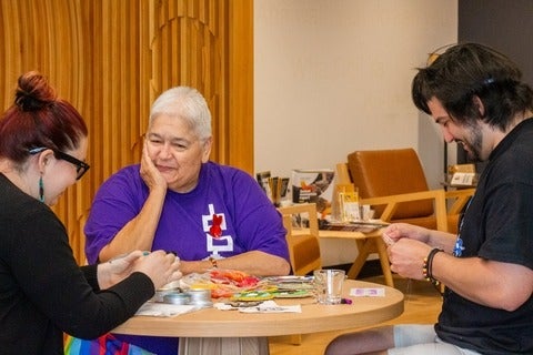 Rhea Green with Indigenous student and staff working on beadwork at a round table