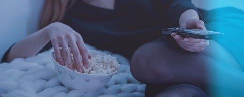 Person on bed with remote in hand watching TV
