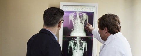 Doctor pointing to x-ray results to man wearing black suit