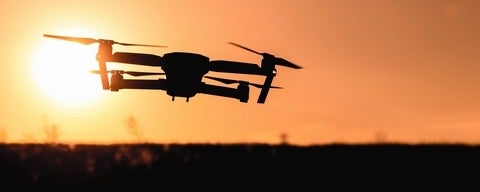 Drone flying towards sunset