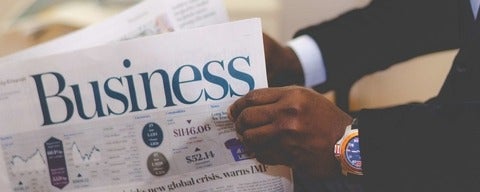 Man holding Newspaper with business in the front 