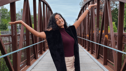 Preet Momi on a bridge with hands thrown up in celebration