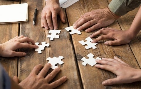 Hands on jigsaw puzzle pieces on a table