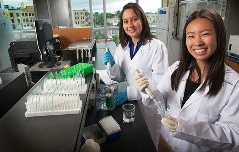 Two female graduate students pipetting in School of Pharmacy lab