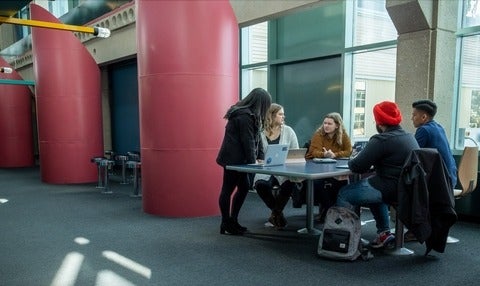 A group of students gather around a table in the Davis Centre