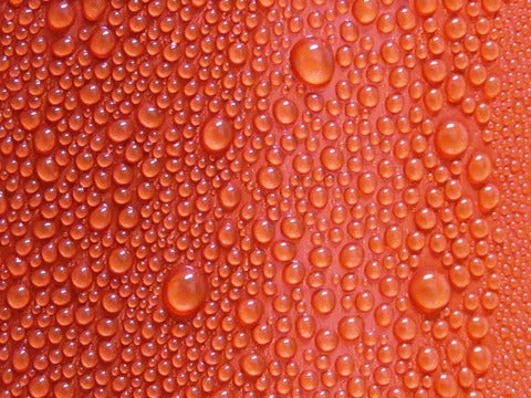 Red surface with sweat-like water beads on it