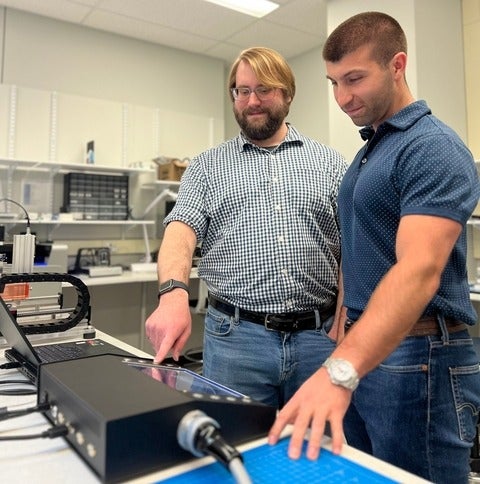 Michael Lavdas (right), CTO of Tenomix, and engineer Jacob Tryon working with the benchtop device's display screen.