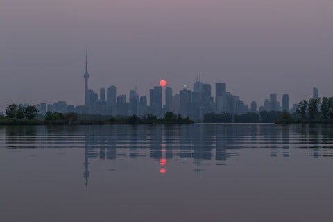 Red sunset over Toronto's skyline caused by wildfire pollution.
