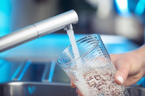 A person filling a glass of water.