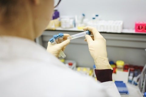 Scientist in lab examining test tubes