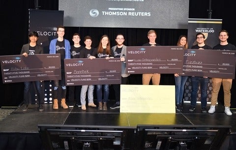 Velocity 25k winners hold up their cheques and smile at the camera.