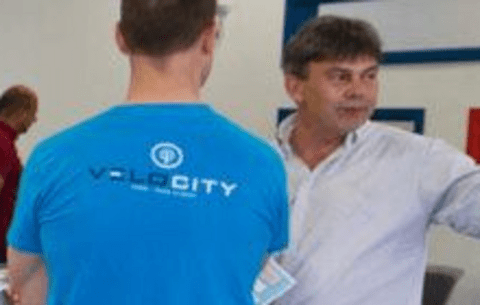 Student in Velocity shirt speaking to an open house attendee