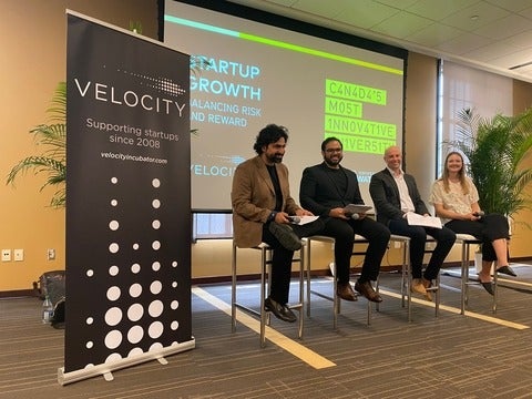 A panel of speakers from Velocity sitting in front of a screen